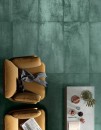 Mirage Lemmy LY 06 Viridium 60x120. Głęboka, patynowana zieleń podłogi kontrastuje z miodowymi fotelami oraz minimalistycznym stolikiem z kawą i owocami. Nowoczesna aranżacja o surowym, a zarazem przytulnym sznycie.