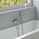 Oltens Vernal bateria wannowo-prysznicowa ścienna chrom 34004100 - bateria zamontowana na ścianie w jasnej łazience z białą wanną oraz oknem