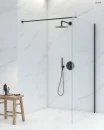 Oltens Bo Walk-In ścianka prysznicowa 110 cm czarny mat/szkło przezroczyste 22003300 - ścianka zamontowana w jasnej łazience z białymi płytkami oraz czarnym zestawem prysznicowym