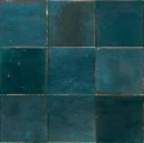 Marazzi Lume Blue Lux w formacie 10x10. Charakteryzują się głębokim, morskim odcieniem niebieskiego z efektem postarzania i wyraźnymi różnicami tonalnymi. Błyszcząca powierzchnia i nieregularne krawędzie nadają im rzemieślniczy styl.