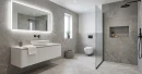 Gres Blustyle Unica Stone 60x120 w łazience z podwieszaną szafką, nablatową umywalką i lustrem LED. W tle wisząca toaleta, strefa prysznicowa walk-in z czarną armaturą, wnęka na kosmetyki oraz wiklinowy kosz. Naturalny, kamienny wygląd.