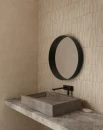 Wizualizacja minimalistycznej łazienki ze ścianą wyłożoną płytkami Marazzi Slow Wall 3D Hay Gesso 40x120 cm MPC9 o wyraźnej, pionowej fakturze prążków. Widoczna jest betonowa, prostokątna umywalka, czarna bateria i wiszące, okrągłe lustro w czarnej ramie.