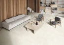 Gres Itiles La Piase White Naturale 60x120 w jasnym salonie. Kremowa podłoga o strukturze kamienia współgra z drewnianymi panelami ściennymi, jasną sofą i nowoczesnym regałem. Dwa szare fotele oraz drewniany stolik kawowy dopełniają eleganckie wnętrze.