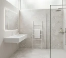 Gres Alaplana Gravina White Mate 120x120 na podłodze i ścianie jasnego salonu z aneksem kuchennym. Płytki o wzorze lastryko tworzą spójną bazę dla drewnianych mebli, białej sofy i nowoczesnego regału. Wygodna i świetlista przestrzeń, również w łazience.