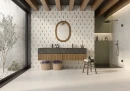 Gres Keraben Terracota Blanco Naturale 60x60 na podłodze jasnej łazienki. Matowe płyty tworzą bazę dla dekoracyjnej ściany z geometrycznym wzorem oraz drewnianych belek stropowych. Zielone kafelki pod prysznicem i roślinność nadają wnętrzu charakteru