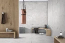 Industrialna aranżacja domowej siłowni z płytkami Prime Ceramics Festive Bianco Carving. Jasnoszary gres 60x120 o surowym wyglądzie betonu doskonale współgra z drewnianymi lamelami. Trwałe i stylowe rozwiązanie do stref aktywności.