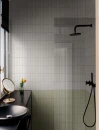 Nowoczesna łazienka z prysznicem walk-in i czarną armaturą, ściany wykończone płytkami cegiełkami Marazzi Confetto Salvia 5x15 cm MDTS w jasnozielonym, szałwiowym odcieniu o półmatowej powierzchni.
