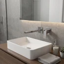 Noken Square 100318380- chromowana, podtynkowa, jednouchwytowa bateria umywalkowa w nowoczesnym geometrycznym designie  na ścianie wyłożonej płytkami imitującymi szary kamień. Drewniana szafka z białą umywalką nablatową. Podświetlane lustro na ścianie.