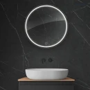 Oltens Nordlis lustro 60x60 cm okrągłe z oświetleniem z przodu z matą grzewczą czarny 64100300 - lustro powieszone w łazience na ścianie z ciemnymi płytkami oraz białą umywalką