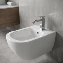 Noken Square 100263948- chromowana, stojąca, jednouchwytowa bateria bidetowa bez korka w kolorze chromu ustawiona na podwieszanym białym bidecie. Szare płytki gresowe imitujące beton ułożona na ścianach i podłodze.