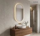 Oltens Nordlis lustro 50x100 cm owalne z oświetleniem od tyłu z matą grzewczą mosiądz szczotkowany 64129510 - lustro zawieszona na ścianie w łazience gdzie znajduje się drewniana szafka razem z umywalką oraz prysznic