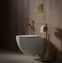 Aranżacja łazienki w minimalistycznym stylu z drewnopodobną ścianą, białą wiszącą misą wc, stojakiem na papier oraz baterią bidetową podtynkową Omnires Y kolor mosiądz szczotkowany SYSYBI2BSB