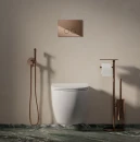 Aranżacja łazienki w minimalistycznym stylu z beżową betonową ścienną, marmurową podłogą, białą wiszącą misą wc, miedzianym stojakiem na papier oraz miedzianą baterią bidetową podtynkową Omnires Y - SYSYBI2CP