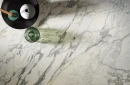 Gresowa płytka imitująca biały marmur z szarymi i beżowymi żyłami Sichenia Prestige Arabesque Satin 3D 60x60 ułożona na podłodze. Dekoracja w postaci czarnego podstawka, wazonów i zapachu z patyczkami.