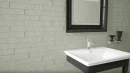 CIL Grace Clari Gloss 5X25- zielona płytka cegiełka na ściany w połysku na ścianie łazienki. Czarna szafka z białą umywalką, prostokątne lustro w czarnej ramie.