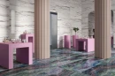 Wielkoformatowa, gresowa płytka imitująca marmur z fioletową żyłą Sant'Agostino Star Marble Purple Krystal 120x278 CSASMPK227 w połysku na ścianie sklepu. Dwie kremowe kolumny o strukturalnej powierzchni. wielobarwna kamienna posadzka, różowe stoliki.