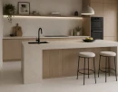 Nowoczesna kuchnia z wyspą wykończona płytkami Marazzi SistemT Cromie Chiaro 30x30 cm MHMM. Jasnoszare płytki inspirowane naturalnym kamieniem tworzą elegancką, minimalistyczną przestrzeń harmonijnie połączoną z drewnianą zabudową.