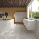Fap Ceramiche Materia Eclecttica Bianco Matt R10 60x120- Szara płytka gresowa imitująca lastryko z wielokolorowym oczkiem na podłodze kuchni. Biała zabudowa kuchenna, biała wyspa kuchenna. Żółta ściana stanowiąca piękny kontrast do szarego terazzo.