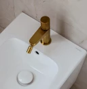 Łazienka z beżową marmurową płytką ścienną, białym bidetem oraz baterią bidetową stojącą Omnires CONTOUR w kolorze złota szczotkowanego CT8020GLB