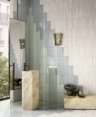 Delconca Ghiaccioli GH 2 Anice Brick 6x25- niebieska płytka cegiełka na ściany w połyskującym wykończeniu na ścianie łazienki w połączeni z zieloną oraz kremową płytką. Wolnostojąca umywalka wykonana z kremowego kamienia,