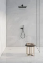 Ceracasa Davos Ice Polished 120x120- gresowa płytka imitująca jasny szary kamień z ciemnymi przebarwieniami na ścianach kabiny prysznicowej. Kabina typu Walk-In w czarnej ramie. Czarny zestaw prysznicowy podtynkowy.