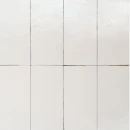Układ pionowy kilku jasnokremowych płytek Marazzi Terramater Vaniglia Lux 18,6x37,5 cm. Kafle połączone ciemną fugą, ukazujące błyszczącą, drobnoziarnistą fakturę powierzchni, która delikatnie odbija światło w górnej części kadru.