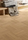 Brązowa płytka gresowa imitująca drewno z wyraźnymi słojami Imola Mother Mirra6 SL 2012 20x120 w formie klepki na podłodze sypialni. Rama łóżka wykonana z jasnego dębowego drewna, szary koc i narzuta.