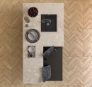 Gresowa płytka imitująca drewniany przebarwiany chevron Ecoceramic Loire Maple 60x120 na podłodze kuchni. Wyspa kuchenna wykonana z jasnego beżowego lastryka. Grafitowy zlew i bateria zlewozmywakowa.