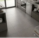 Nowoczesna aranżacja kuchni z podłogą wyłożoną kwadratowymi, ciemnoszarymi płytkami gresowymi Marazzi SistemT Graniti Grigio Scuro Rock 30x30 cm M7JZ o wyraźnej, strukturalnej powierzchni imitującej granit.