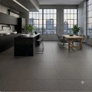 Industrialna kuchnia z podłogą z ciemnoszarych, kwadratowych płytek imitujących beton Marazzi SistemT Graniti Grigio Scuro 30x30 cm MRTE. Wnętrze uzupełnia czarna zabudowa kuchenna, wyspa oraz drewniany stół jadalniany.