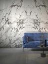 Wnętrze z niebieską sofą i marmurowymi płytkami ściennymi Marazzi Grande Marble Look Capraia