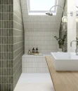 Gayafores Deco River Green 32x62,5- ścienna dekoracyjna płytka w zielonym kolorze i połyskującym wykończeniu na ścianie łazienki w połączeniu z płytką w kolorze Clay. Drewniany podwieszany blat łazienkowy, biała umywalka nablatowa.