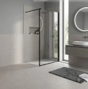 Minimalistyczna łazienka z szarymi płytkami Marazzi SistemT - Graniti Grigio Chiaro Diamond 20x20 cm MEC2 na podłodze i ścianach. Wnętrze z czarnym prysznicem typu walk-in, okrągłym lustrem, szafką i umywalką. Wysokie okno wychodzi na zieleń.