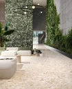 Lobby z płytkami Sant'Agostino Venistone Beige 60x60. Beżowe, matowe lastryko z dużymi jasnymi oczkami ociepla surowy, industrialny beton i zieleń roślin. Włoski design łączący naturę z loftowym stylem.