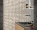 Aranżacja kuchni ze ścianą z białych trójwymiarowych płytek WOW 3DB Diamond Quartz Gloss 12,5x25 cm (135538). Błyszczące cegiełki 3D ułożone z wyrazistą fugą tworzą tło dla ciemnego zlewu z baterią, drewnianych szafek i wiszącej białej półki.
