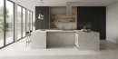 Maxibox Tivoli Light Grey Matt Carving 60x120- gresowa płytka imitująca szary beton w matowym wykończeniu na podłodze kuchni. Czarne fronty zabudowy kuchennej. Wyspa kuchenna z wydzielonym miejscem do jedzenie i gotowania.
