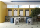 Vives Surf Waikiki Azul-B 23x33,5 strukturalna ścienna lamelowana płytka dekoracyjna w ciemnoniebieskim kolorze na podestach stołu w restauracji. Patchworkowe płytki na ścianie oraz geometryczne wielokolorowe na podłodze