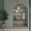 Stylowy salon z matowymi płytkami WOW Bits Square Kale 11,6x11,6 cm 133026. Wnęka ścienna i podłoga ułożone w geometryczną kratę z akcentami różu i bieli. Całość dopełnia czarna konsola, nowoczesne wiszące lampy oraz roślina w złotej donicy.