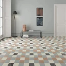 Aranżacja nowoczesnego wnętrza z wzorzystą podłogą ułożoną z kwadratowych płytek. Błyszczące, ciemnoszare akcenty WOW Bits Square Storm Gloss 11,6x11,6 cm tworzą wyrazisty geometryczny motyw z płytkami w odcieniach beżu, szarości i bieli.