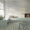 Jasny salon z kominkiem i narożnym siedziskiem. Zielone, matowe płytki WOW Bits Kale 3,7x11,6 cm tworzą geometryczny motyw na podłodze, przeplatając się z białymi akcentami i współgrając z jasną zabudową wokół kominka.