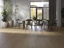 Jadalnia z drewnianym stołem, drewnianymi krzesłami z czarnym skórzanym obiciem i płytkami podłogowymi brązowymi drewnopodobnymi Cifre Adena Walnut Mate XS 30x120