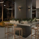 Eleganckie wnętrze restauracji z kolumną wyłożoną czarnymi płytkami 3D WOW Faces Valley Coal 5x40 131513. Przy blacie ze zintegrowaną zielenią stoją drewniane stołki barowe, a nastrojowe oświetlenie podkreśla strukturę ściany.