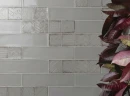 Ściana z płytkami Cifre Alchimia Decor Pearl Brillo 7,5x30 w połysku w kolorze szarym o nieregularnej strukturze, z dekoracyjnym kwiatem.