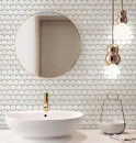 Elegancka łazienka z białą umywalką nablatową, złotą baterią, okrągłym lustrem, złotymi wiszącymi lampami oraz białą dekoracyjną mozaiką ścienną z efektem 3D Ceramik Studio 3D Hex Snow 30x27,4