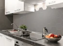Kuchnia z białymi szafkami, marmurowym blatem i szarą mozaiką dekoracyjną w kształcie heksagonów ze strukturalną powierzchnią Ceramik Studio Heksagon Relief Light Grey 36x25
