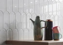 Ściana z hiszpańskimi płytkami w kolorze białym Cifre Alma Scale Pure Brillo 8x21,5 w kształcie rybiej łuski z drewnianym blatem i kolorową ceramiką.