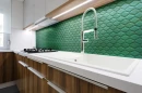 Kuchnia z drewnianymi szafkami, białym blatem, chromowaną baterią i zieloną mozaiką ścienną w kształcie rombów Ceramik Studio Daring Emerald 30,5x30,8
