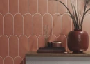 Ściana z matowymi hiszpańskimi płytkami, w kształcie rybiej łuski Cifre Alure Scale Terra Mate 8x21,5, konsolą, ceramicznym wazonem z suszonymi trawami, świecą i  książkami.