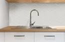 Kuchnia z białymi szafkami, drewnianym blatem, stalowym zlewozmywakiem, chromowaną baterią oraz białą mozaiką ścienną w kształcie rombów Ceramik Studio Romb White Glossy 2 - 21x24