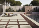 Strefa z płytkami imitującymi beton, tarasowymi, antypoślizgowymi Cifre Acron Ivory Mate Rc 20Mm Antislip 60x60 20MM, z leżakami, ścieżką z płyt wtopionych w kamienie, z basenem, murkiem z egzotycznymi kaktusami i sukulentami.